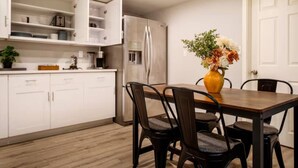 A modern kitchen with white cabinets, a stainless steel refrigerator, and a dining table with chairs. - Modern Cozy Bright 2BR Lower Unit w/private entry (Seattle)