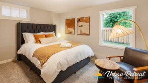 A bedroom with a large bed, a chair, a lamp, and artwork on the wall. - Modern Cozy Bright 2BR Lower Unit w/private entry (Seattle)