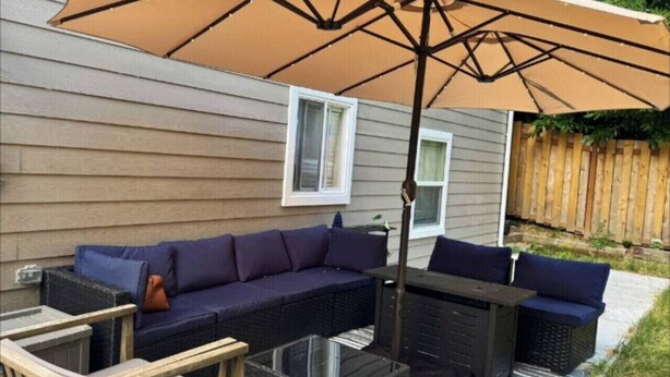 A patio with a sectional sofa, a table, and an umbrella. - Modern Cozy Bright 2BR Lower Unit w/private entry (Seattle)