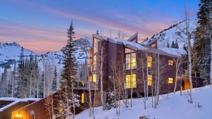 A modern mountain cabin with large windows, surrounded by snow-covered trees and mountains. - Enjoy pure luxury in Alta in this Contemporary Condominium with Hot Tub (Alta)