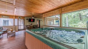 A wooden deck with a hot tub, wicker furniture, and a view of the forest. - STERLING LODGE - LUXURY MOUNTAIN VIEW CABIN (Sautee Nacoochee)