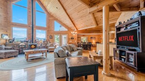 A spacious wooden interior with a fireplace, a large sofa, a TV, and a dining area. - STERLING LODGE - LUXURY MOUNTAIN VIEW CABIN (Sautee Nacoochee)