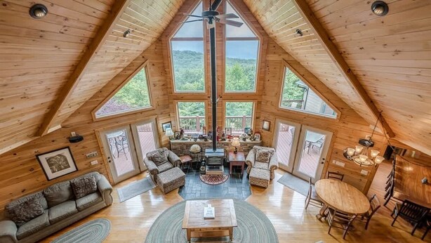A spacious loft with a high ceiling, large windows, a fireplace, and a cozy seating area. - STERLING LODGE - LUXURY MOUNTAIN VIEW CABIN (Sautee Nacoochee)