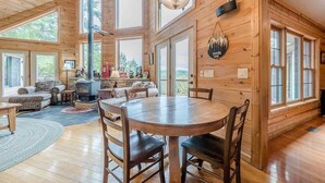 A wooden cabin interior with a dining area, fireplace, and large windows. - STERLING LODGE - LUXURY MOUNTAIN VIEW CABIN (Sautee Nacoochee)