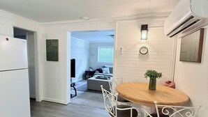 A modern kitchen with white cabinetry, a white refrigerator, a round wooden table with white chairs, and a small potted plant. - Comfort meets charm (Fayetteville)