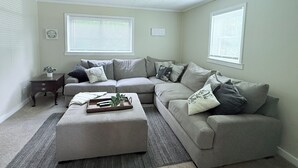 A living room with a sectional sofa, a small side table, and a tray with decorative items. - Comfort meets charm (Fayetteville)