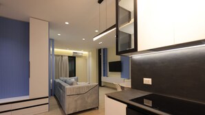 A modern kitchen with a built-in stove, a grey sofa, and a blue accent wall. - Illyrian Apartment 02 (Durrës)
