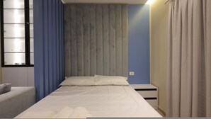 A bedroom with a bed, a nightstand, a dresser, a window with blinds, and a curtain. - Illyrian Apartment 02 (Durrës)