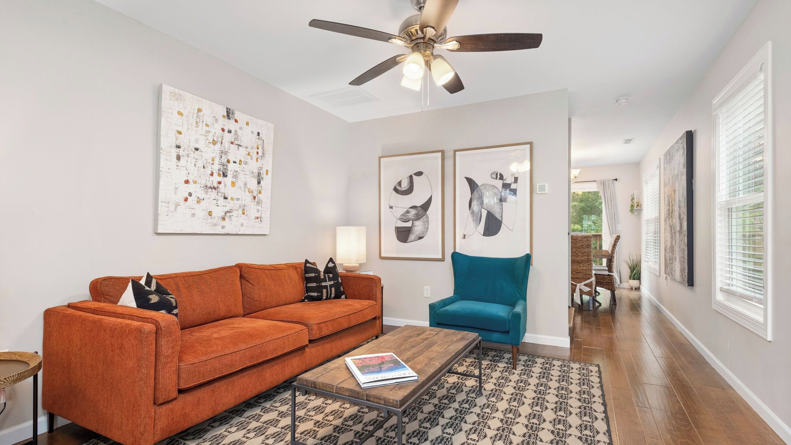 A living room with a sofa, a coffee table, a chair, and artwork on the walls.