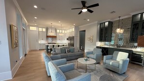 A spacious living area with a modern kitchen in the background, featuring a central island and contemporary furniture. - The Kentwood- A Luxury Home in Baton Rouge- minutes from LSU and downtown! (Baton Rouge)