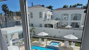 Uitzicht vanaf een balkon met een zwembad, ligbedden en parasols.