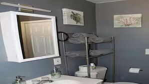 A bathroom with a white sink, a mirror, a toilet, and a towel rack. - Spacious 2-Bedroom Retreat in San Jacinto; Sleeps 6, AC & Pet-Friendly (San Jacinto)
