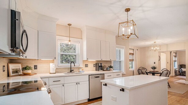 A modern kitchen with white cabinetry, a central island, and pendant lighting. - The Park Circle Haven ~ Spacious 5br/4ba Home! (North Charleston)