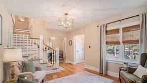 A spacious living room with a staircase, a chandelier, and a view of the outdoors. - The Park Circle Haven ~ Spacious 5br/4ba Home! (North Charleston)