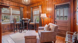 A wooden-paneled room with a wooden door, a table with chairs, a lamp, and a cushioned bench. - The Park Circle Haven ~ Spacious 5br/4ba Home! (North Charleston)