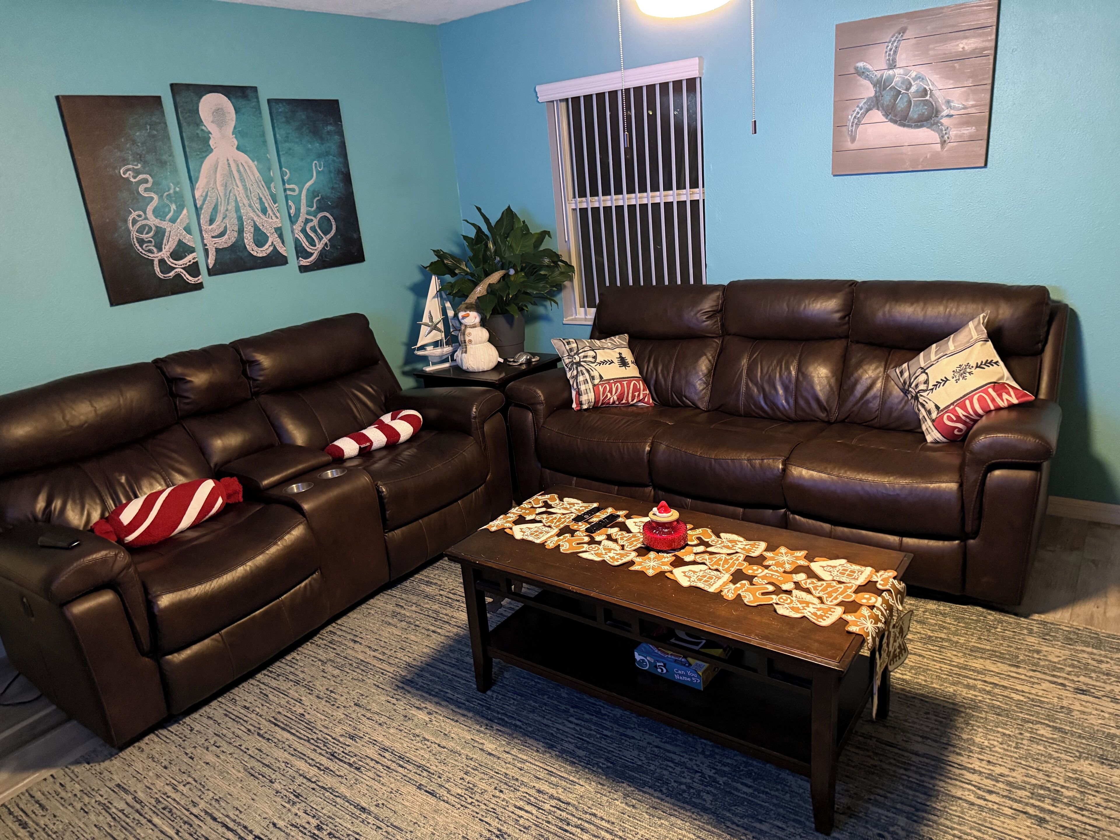 A living room with two brown leather sofas, a coffee table with gingerbread cookies, and wall art depicting sea creatures.
