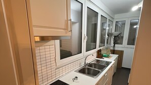 A modern kitchen with white cabinets, a black stovetop, and a double sink. - Cozy 2-bedroom apartment in center Durres (durres)