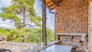 Un espacio de estar al aire libre rústico, con pared de piedra, techo de madera y sillas de mimbre.