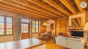 Una habitación rústica con techo de madera, paredes de piedra, una mesa de comedor con sillas, un sofá y una chimenea.