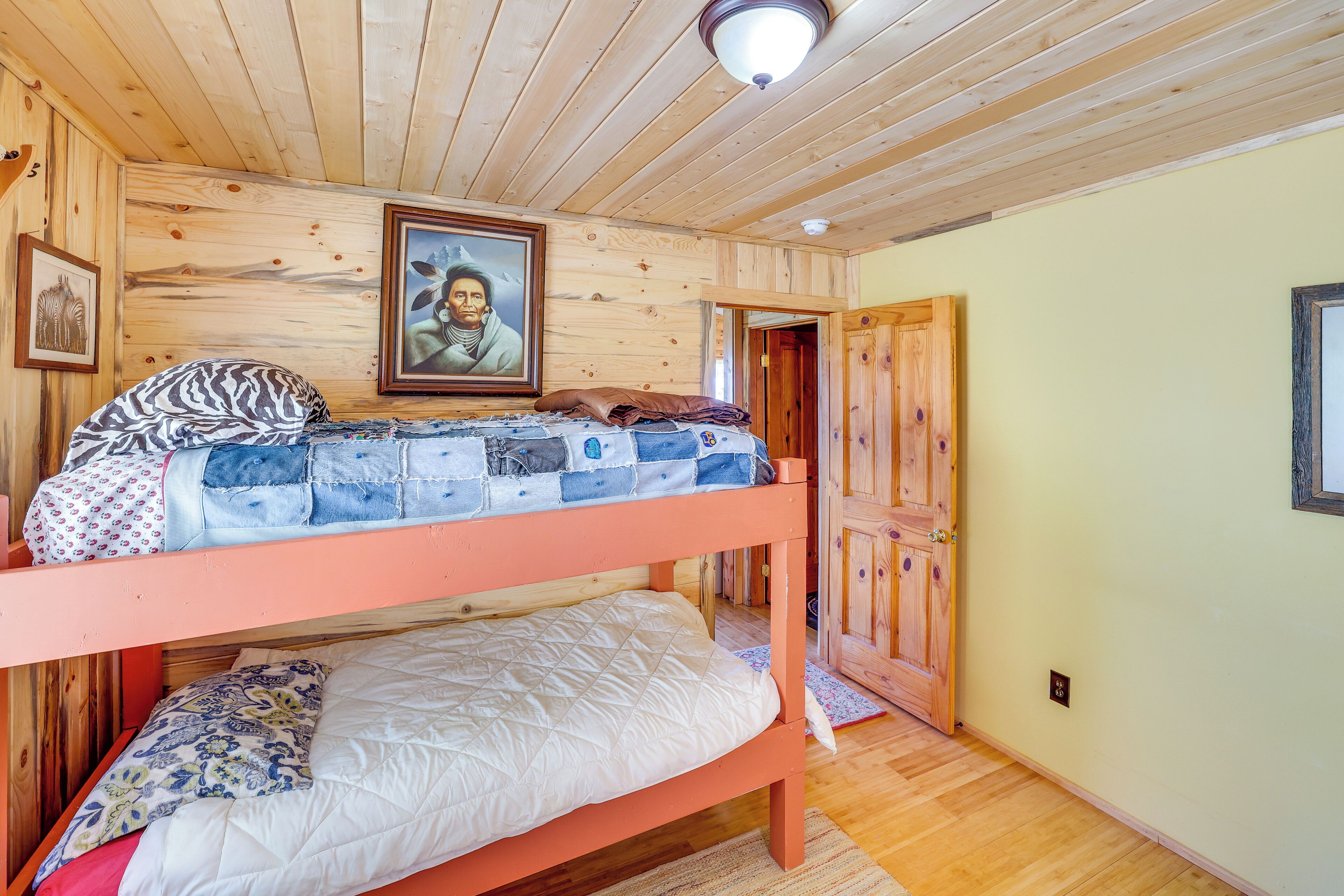A bunk bed room with wooden walls and a ceiling light.