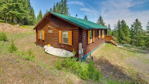 A wooden cabin with a green roof, surrounded by trees. - Pet-Friendly Cabin on 10 Acres in Joseph: Private! (Joseph)