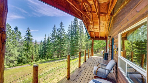 A wooden deck with a view of a forest. - Pet-Friendly Cabin on 10 Acres in Joseph: Private! (Joseph)