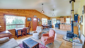 A cozy log cabin interior with a dining area, kitchen, and a large fireplace. - Pet-Friendly Cabin on 10 Acres in Joseph: Private! (Joseph)