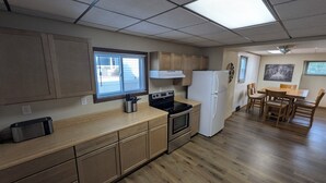Une cuisine compacte avec des meubles en bois, une cuisinière, un réfrigérateur et un coin repas comprenant une table et des chaises.