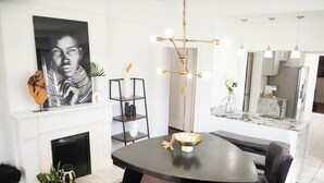 A dining area with a black table, chairs, a chandelier, a fireplace, and a kitchen in the background. - 2 Mi to Mercedes-Benz Stadium! Updated ATL Home (Atlanta)