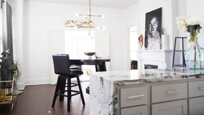 A modern kitchen with a marble countertop, a dining area with a black chair, and a pendant light. - 2 Mi to Mercedes-Benz Stadium! Updated ATL Home (Atlanta)