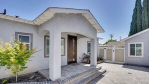 A modern two-story house with a covered porch, a small garden, and a paved driveway. - 2 Mi to Disneyland: Home w/ Furnished Patio! (Anaheim)