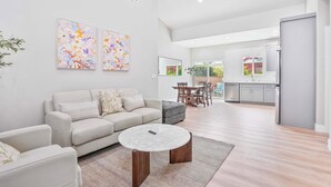 A modern living room with a sofa, coffee table, and artwork on the wall. - 2 Mi to Disneyland: Home w/ Furnished Patio! (Anaheim)