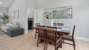 A dining area with a wooden table and chairs, a grey ottoman, and a potted plant. - 2 Mi to Disneyland: Home w/ Furnished Patio! (Anaheim)