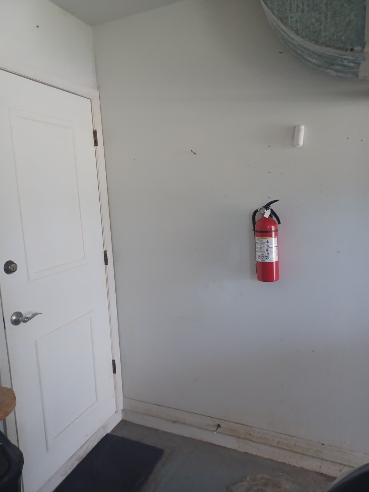 A white door with a doorknob and a fire extinguisher mounted on the wall.