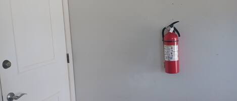 A white door with a doorknob and a fire extinguisher mounted on the wall.