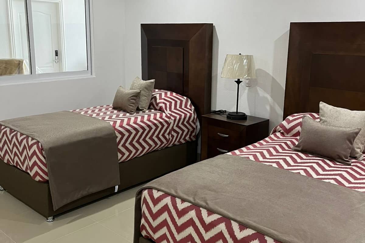 Una habitación de hotel con dos camas, una mesita de noche y una lámpara.