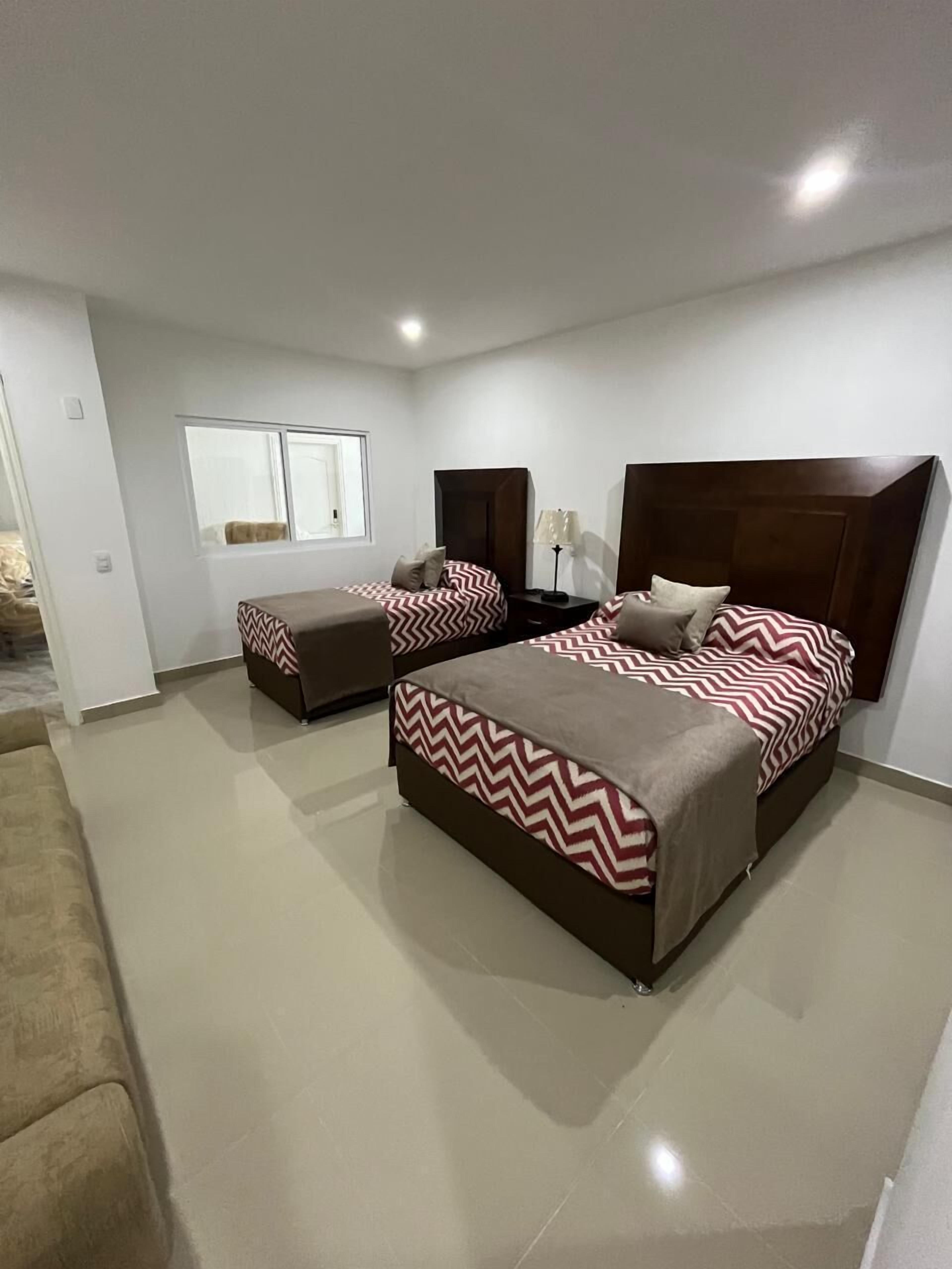 Un dormitorio moderno con dos camas, un ventanal grande y suelo llano.