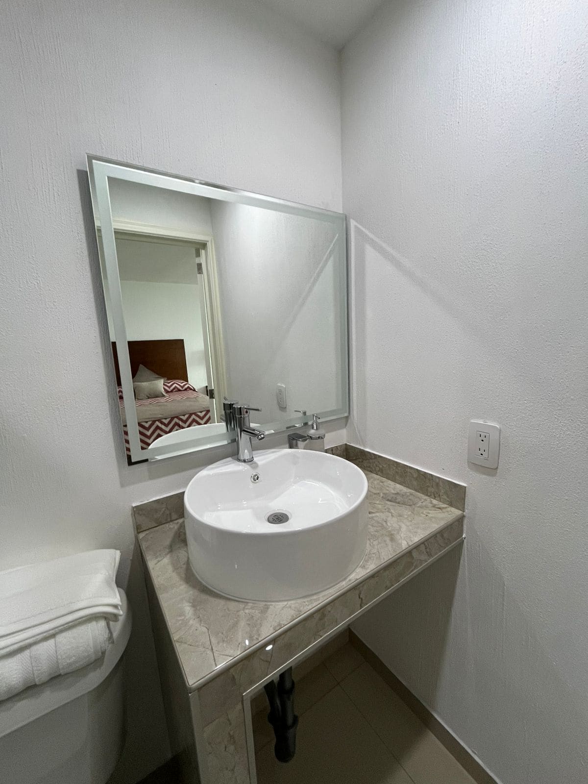 A bathroom with a white sink, a mirror, and a towel rack.