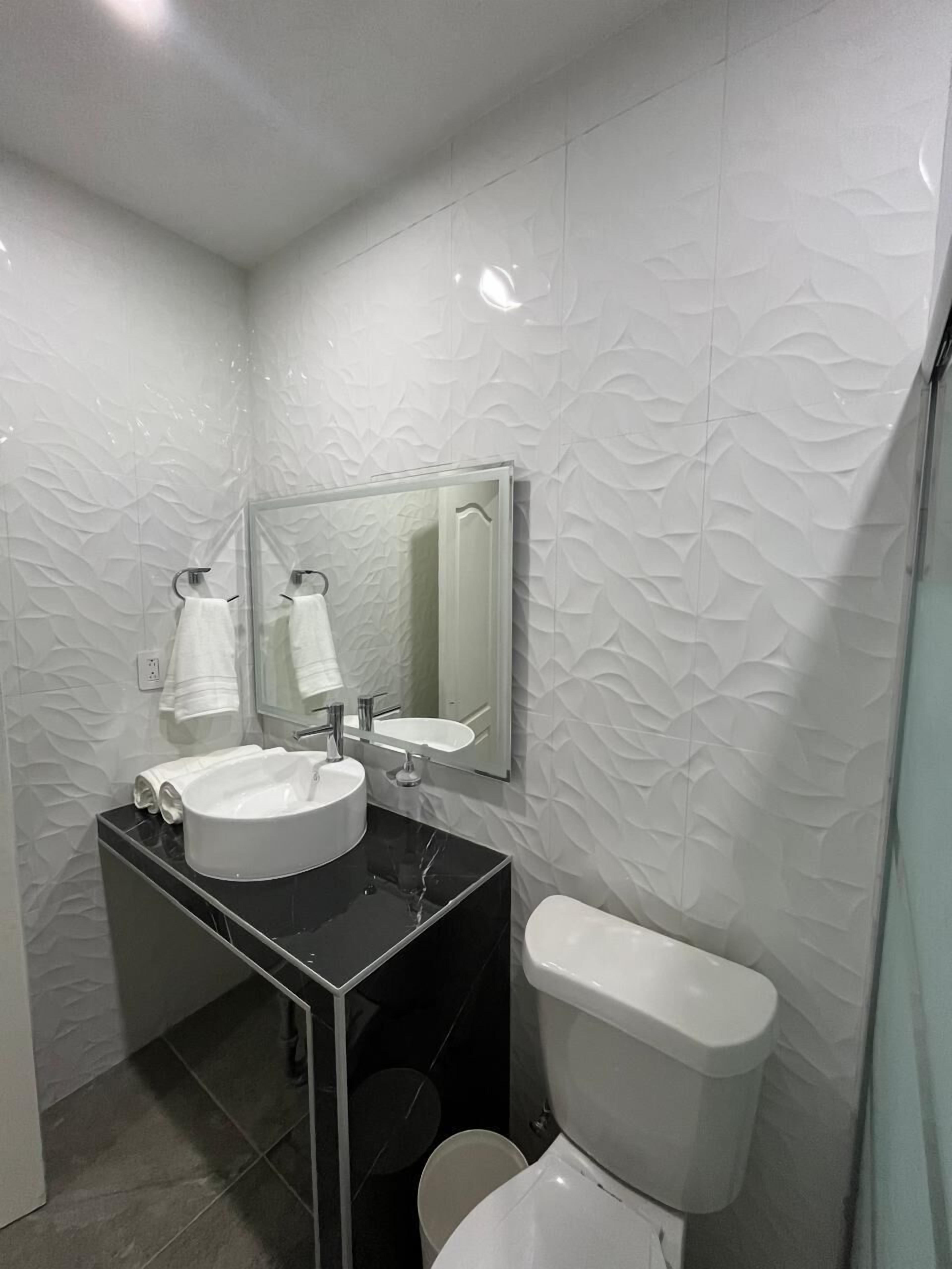 A modern bathroom with a white sink, mirror, and toilet.
