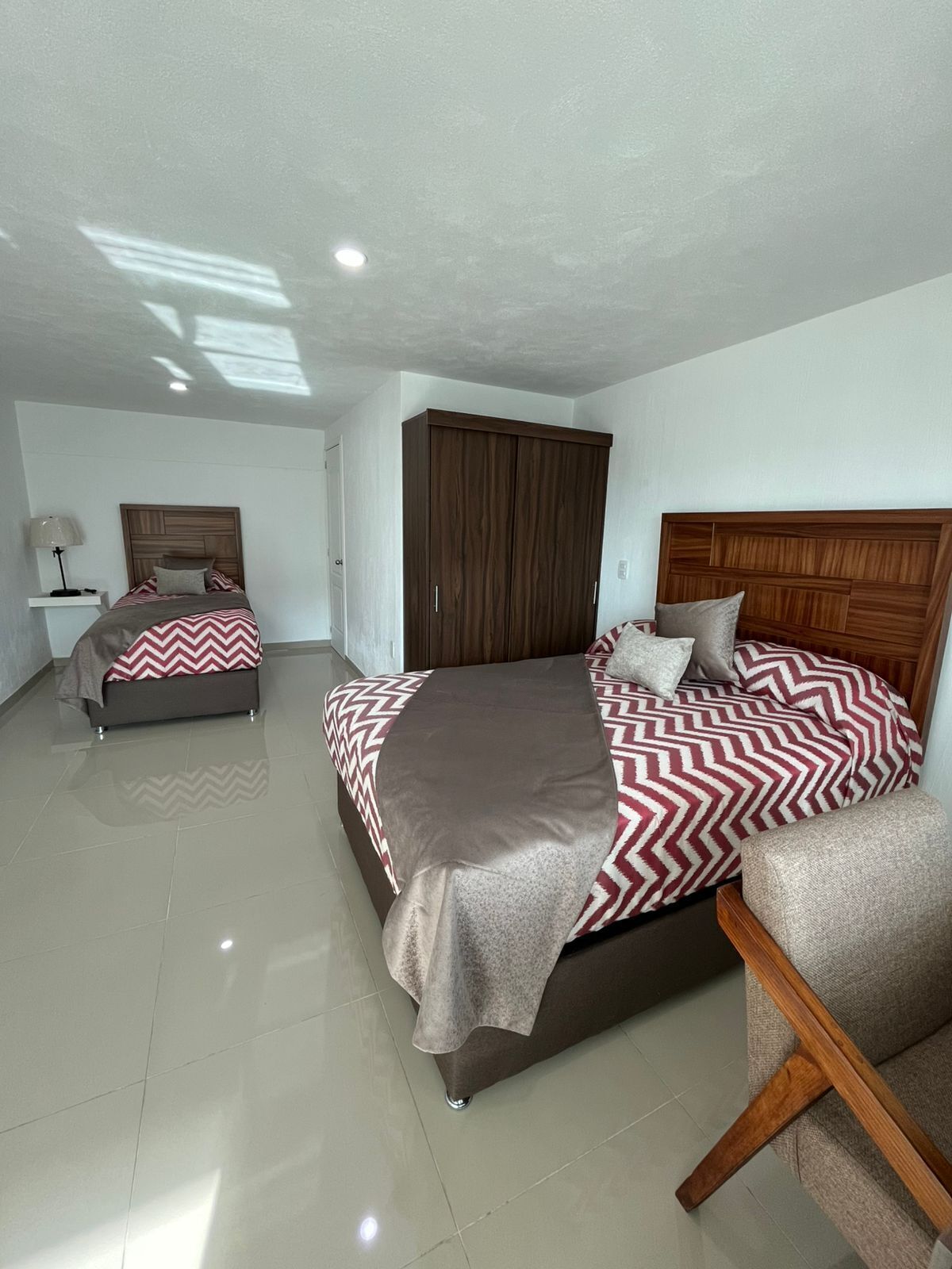 Un dormitorio con dos camas, un armario y una mesita de noche.