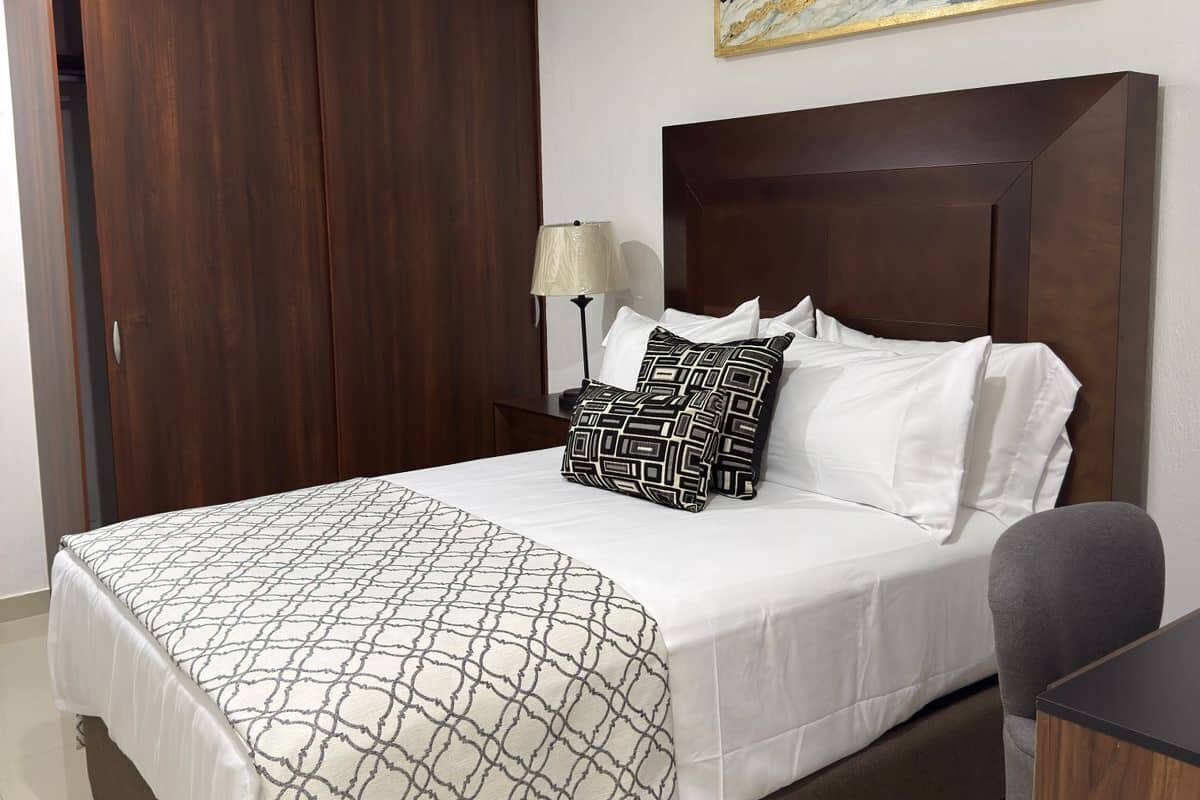 Habitación de hotel con una cama grande, un armario, un escritorio y un cuadro en la pared.