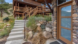 A wooden house with a stone exterior, a wooden staircase, and a large glass door.