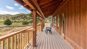 A wooden deck with a view of a hilly landscape.