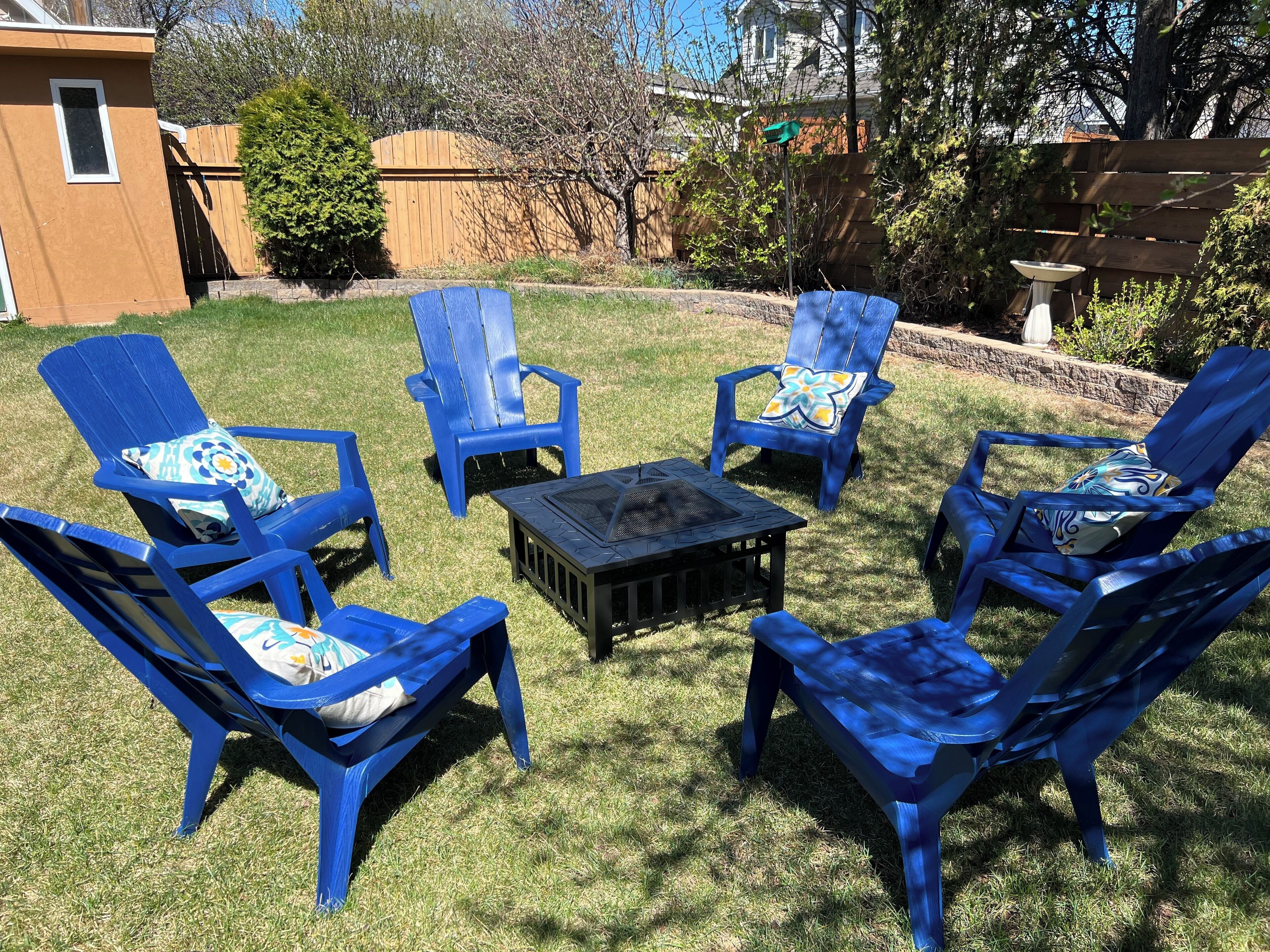 A backyard with blue lawn chairs and a small table.