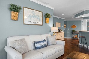 A living room with a sofa, cushions, a map, and wicker baskets. - Relaxing Walk-In Condo •Community Pool • Pet Friendly (Branson)