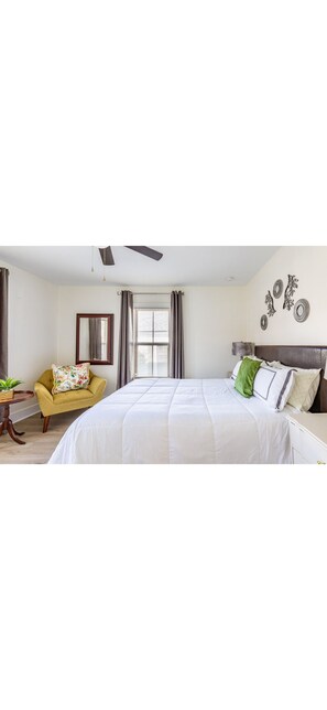 A bedroom with a bed, a chair, a table, a window, and wall decorations.