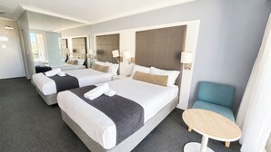 A hotel room with two beds, a small round table, and a blue chair.