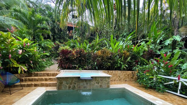 Una piscina rectangular con borde de piedra y una pequeña cascada.