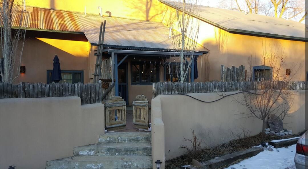 The entrance to Unit #3 in a historic mill house with a wooden fence, steps leading up to the door, and a snow-covered ground.