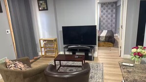 Ett vardagsrum med en soffa, ett soffbord, en tv och en matplats med ett bord och stolar.